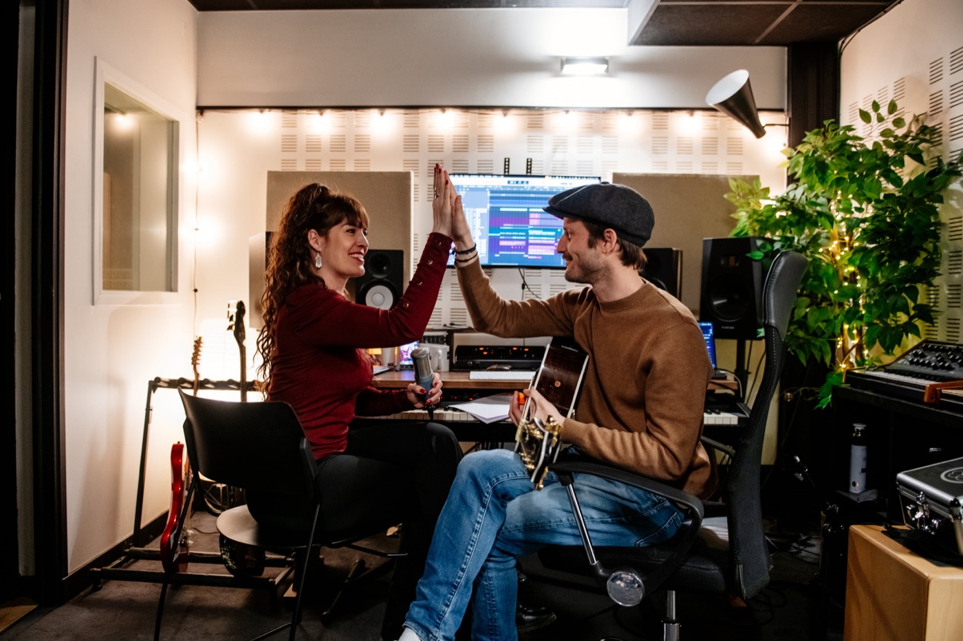 Une artiste et son compositeur se tapent dans la main au studio, guitare en main